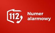 Czerwone tło. Biały kontur Polski a w nim biały napis: 112 i słuchawka telefonu. Z prawej strony biały napis numer alarmowy