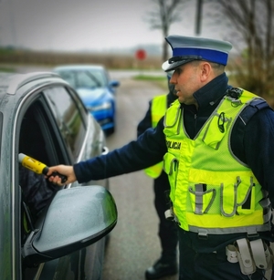 policjant sprawdza stan trzeźwości kierowcy siedzącego w aucie