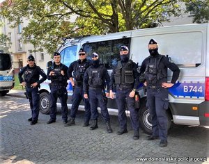 grupa policjantów stoi przed radiowozem