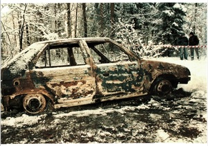 stojący w lesie wrak spalonego samochodu