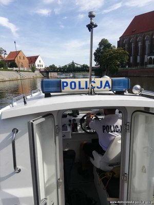 fragment łodzi policyjnej z policjantem w środku, w tle widać moc i rzekę