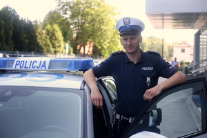 policjant stoi przy radiowozie