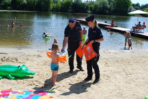 policjanci rozdają materiały dotyczące bezpieczeństwa na kąpielisku