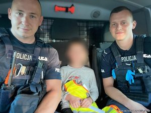 na zdjęciu dwójka policjantów z chłopcem siedzą w radiowozie
