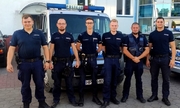 sześciu policjantów stoi przed radiowozem