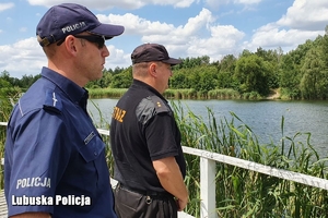 Policjant i strażnik miejski obserwują akwen wodny.