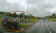screen z wideorejestratora przedstawia samochód, który wjechał na chodnik przy przejściu dla pieszych, na którym grupa osób, w tym dzieci oczekiwali na zielone światło sygnalizatora