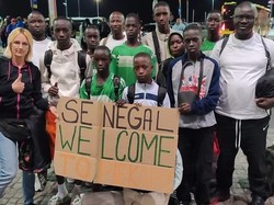 Policjantka po cywilnemu wraz z piłkarzami z Senegalu, którzy trzymają w rękach plakat z napisem: Senegal Welcome to Piekary