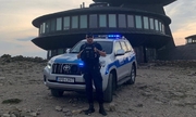 policjant stoi przy radiowozie zaparkowanym przy szczycie Śnieżki