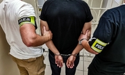 policjanci z zatrzymanym mężczyzną w kajdanach