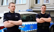 na zdjęciu policjanci w mundurze stoją przy radiowozie
