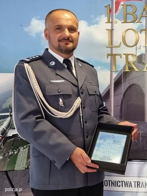 Naczelnik Zarządu Lotnictwa polskiej Policji uhonorowany prezentuje okolicznościową nagrodę.