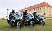 trzej policjanci na nowych motocyklach, w tle budynek