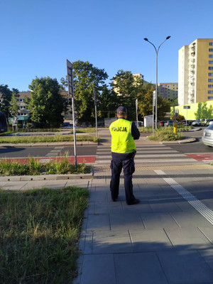 na zdjęciu policjant stoi naprzeciwko przejścia dla pieszych