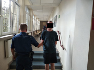 zatrzymany mężczyzna zakuty w kajdanki z policjantem na korytarzu