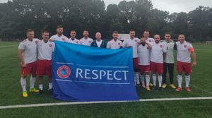 Reprezentacja Polskiej Policji w piłce nożnej stoi na boisku w bramce z rozwiniętym banerem z napisem Respect