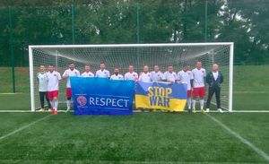 drużyna piłkarska Reprezentacji Polskiej Policji stoi w bramce na boisku z banerami z napisem Respect oraz Stop War