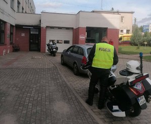 stojące przed szpitalem dwa motocykle policyjne i umundurowany policjant