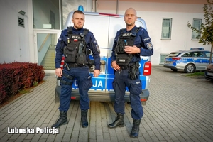 Dwaj umundurowani policjanci przy radiowozie