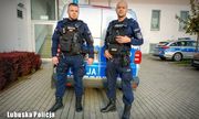 Dwaj umundurowani policjanci przy radiowozie