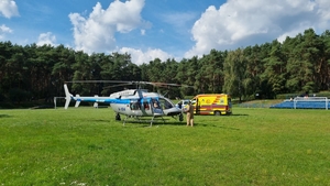 Policyjny Bell 407 GXi na płycie boiska, drugi plan – karetka pogotowia, trzeci plan – radiowóz policyjny