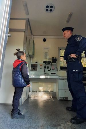 policjant pokazuje chłopcu mobilny posterunek Policji