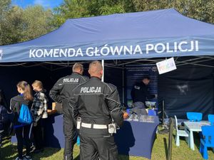 policjanci stojący tyłem przed stoiskiem policyjnym na pikniku z okazji biegu Pamięci Rotmistrza Pileckiego