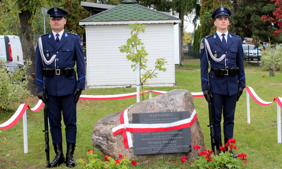dwaj policjanci przy posadzonym dębie i obeliskiem upamiętniającym posterunkowego Feliksa Tołysza