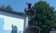 Policjant przy użyciu wózka widłowego próbuje ściągnąć psa z dachu