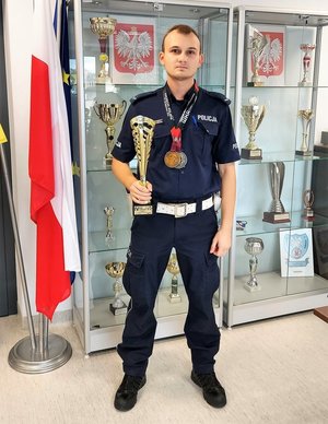 policjant z pucharem i medalami zdobytymi podczas walk karate
