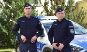 Dwaj policjanci stojący przy radiowozie