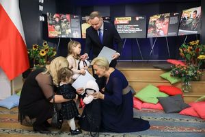 Prezydentowa kuca przy kucającej kobiecie z małą dziewczynką, Prezydent wręcza stojącej obok dziewczynce maskotkę i dużą kopertę