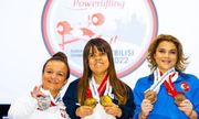 trzy kobiety, sportsmenki z medalami na szyjach stoją obok siebie