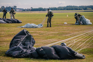 Spadochroniarze zwijają czasze spadochronów po wylądowaniu.