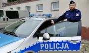 umundurowany policjant stoi w  otwartych drzwiach radiowozu