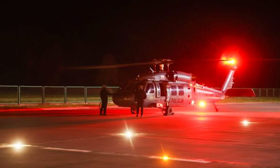 pora nocna. policyjny śmigłowiec na płycie lotniska, a przy nim dwaj funkcjonariusze