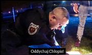 policjant pochyla się nad człowiekiem, któremu udziela pierwszej pomocy