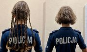 Widok z tyłu. po lewej policjantka w koszulce z napisem Policja na plecach w długich włosach zaplecionych w warkoczyki. Obok, z prawej strony policjantka w koszulce z napisem Policja w krótkich włosach