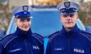 sierż. szt. Elena Kisielewska i asp. Przemysław Śpiewak w mundurze stoją na tle radiowozu