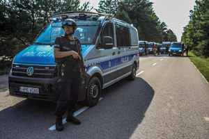 policjant stoi przy radiowozie, w tle zaparkowane na ulicy radiowozy