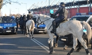 policjanci na koniach podczas zabezpieczania meczu, w tle radiowozy i stadion
