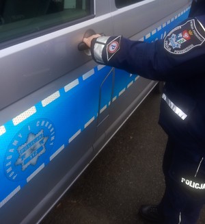 Umundurowany policjant służby prewencyjnej otwiera drzwi radiowozu