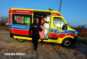 Policjant odprowadza kobietę do ambulansu