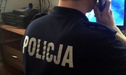 policjant dyżurny widziany od tyłu siedzi przy biurku