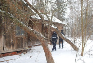 Opuszczony dom, policjanci sprawdzający, czy nikogo w nim nie ma. Dookoła leżący śnieg