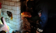 policjant rozpala ogień w piecu kaflowym