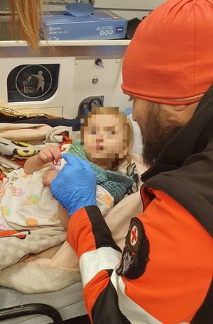 dziecko lezy w karetce obok czuwa ratownik medyczny