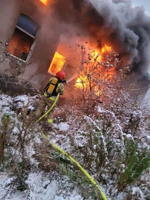 strażak gasi pożar w płonącym domu