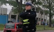 Umundurowany policjant ruchu drogowego podczas służby stoi w rejonie jezdni