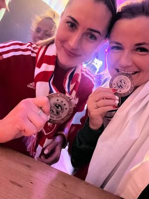 dwie kobiety trzymają w dłoniach medale